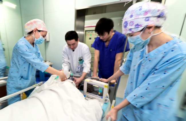 抢救室、手术室、ICU、病房的一体化布局,使被救治的伤员或病人可视病情直接分流,实现了救治各环节的无缝链接,图为重伤者进入ICU接受治疗 抢救室、手术室、ICU、病房的一体化布局,使被救治的伤员或病人可视病情直接分流,实现了救治各环节的无缝链接,图为重伤者进入ICU接受治疗